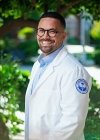 Student in white coat posing for picture.