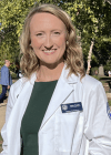 Student posing on campus in white coat