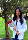 Martina Golaszewski in a white coat photo holding red roses. 