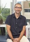 Michele Fornaro profile photo in office setting with plants and books.