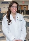 Profile photo of Dr. Melisa Alabsy wearing a white coat in the dental simulation lab.