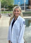 Podiatry student Audrey Diaz stands in her white coat on Glendale campus