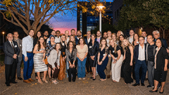 Alumni pose for a group photo during an evening event.