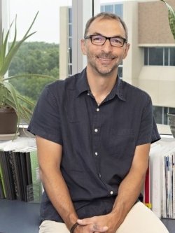 Michele Fornaro profile photo in office setting with plants and books.