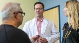 Two doctors talk to a male patient.