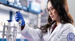 Student conducting tests in a beaker in Midwestern's Research lab.