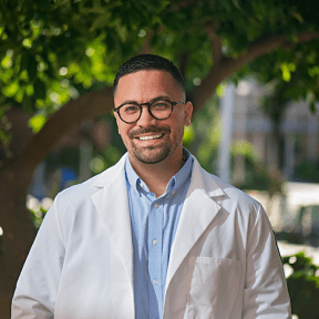 Student in white coat posing outside