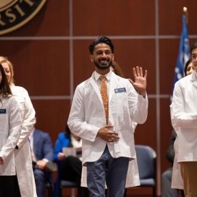 student on stage wearing white coat