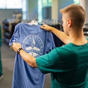 Student looking at t-shirt while student pays at cash register