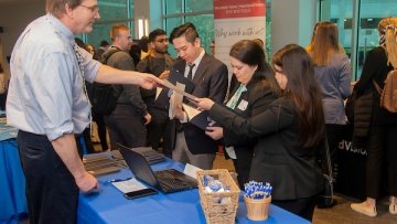 Midwestern Employee passing out brochures at career fair to prospective students.