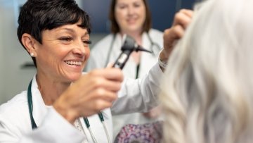 Nurse checking patient's ear.