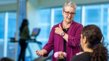 Doctor demonstrates shoulder exercises to woman.