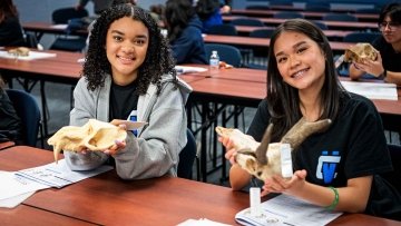 Two high school students holding up bones