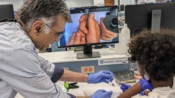 Student learning about dental tools from professor