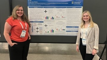 Dr. Prakapenka and Abigail Hegwood stand in front of their research poster.