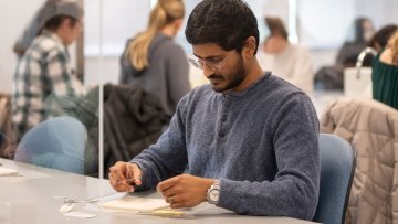 A biomedical sciences student practices suturing techniques. 