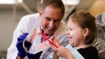 dentist showing child how to brush teeth