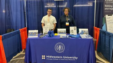 Two faculty stand at table