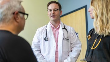 Two providers talk to patient in an exam room