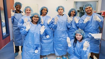 Participants learn to correctly gown and glove for surgery in the mock operating room.