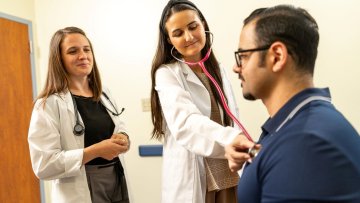 Two women in white coats tend to a patient