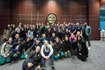 Group of students pose by University seal