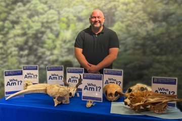 Kevin Manfredi stands by a collection of animal skulls displayed at the Arizona Museum of Natural History