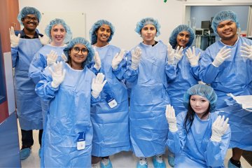 Participants learn to correctly gown and glove for surgery in the mock operating room.