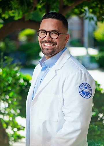 Student in white coat posing for picture.