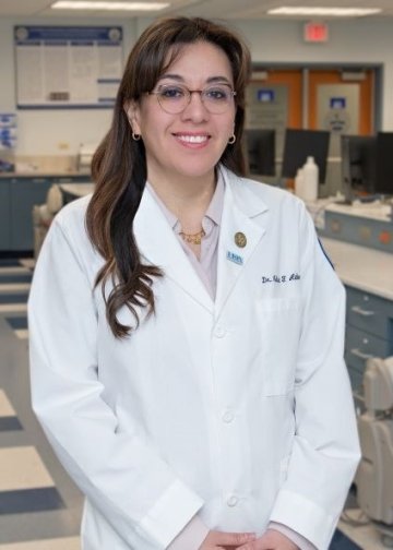 Profile photo of Dr. Melisa Alabsy wearing a white coat in the dental simulation lab.