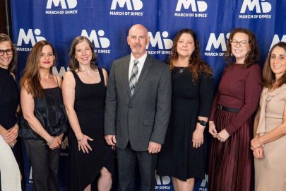 Faculty from the Arizona College of Osteopathic Medicine stand in front of a banner at a March of Dimes event