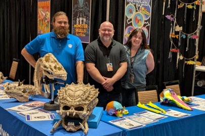 Three anatomy professors stand behind Midwestern's Fan Fusion booth, with various real and fictional skulls on the table