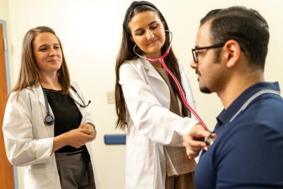 Two women in white coats tend to a patient
