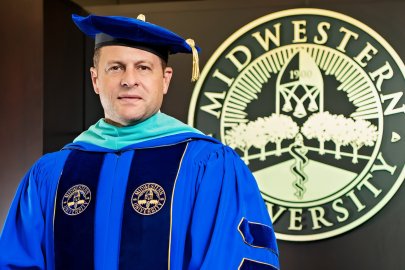 Dr. Joshua C. Baker, President and CEO of Midwestern University, in his academic regalia next to the Midwestern University seal.