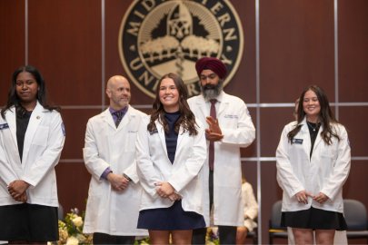 Students in the College of Health Sciences - Downers Grove receive their white coats on stage