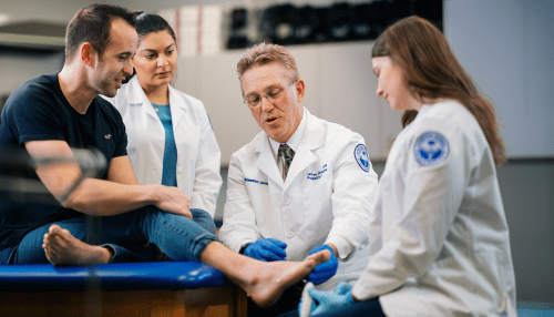 Professor examining foot while students observe