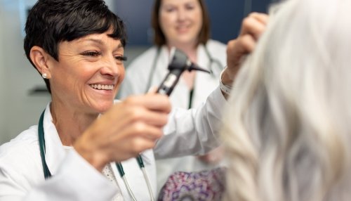 Nurse checking patient's ear.