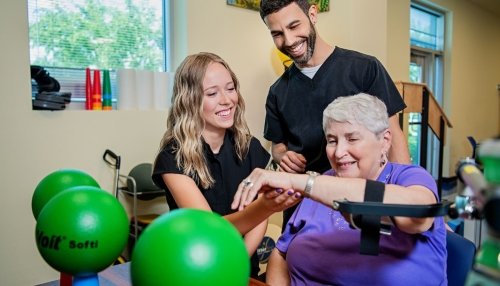 Two occupational therapy students work with a patient.