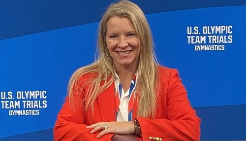 Dr. Lancaster sitting in front of blue Olympics banner