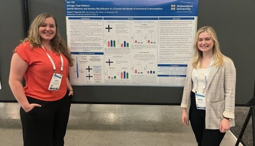 Dr. Prakapenka and Abigail Hegwood stand in front of their research poster.