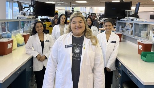 Natalie Ferrufino in white coat posing with fellow students