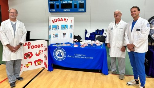 Dr. Durso, Dr. Williams, and dental student William Boensch in white coats in front of their booth at the Senior Fair in Lemont.