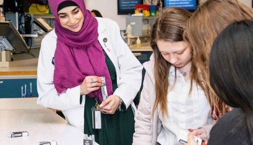 Trainer with high school students in lab