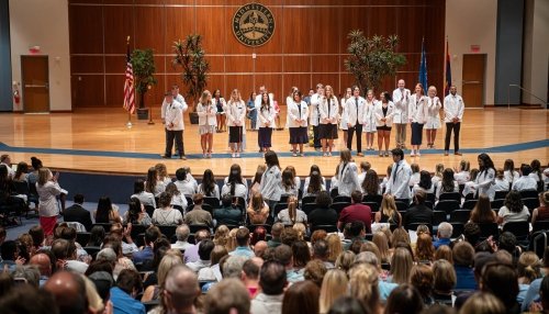 Students on stage wearing their white coats at the Glendale campus.