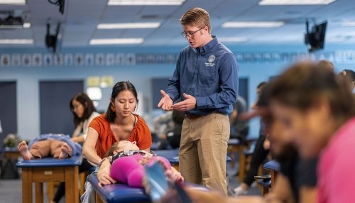 Student making osteopathic adjustment on student patient while professor gives instructions