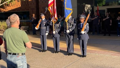 Military personnel stand holding flags.