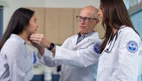 Student and professor examining patients head.