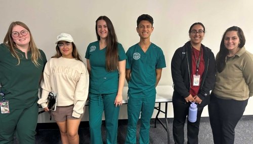 Members of the One Health Club gather for a photo in a line.