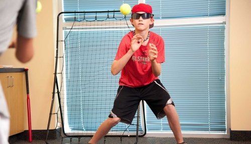 Child in red shirt catching tennis ball to test his vision