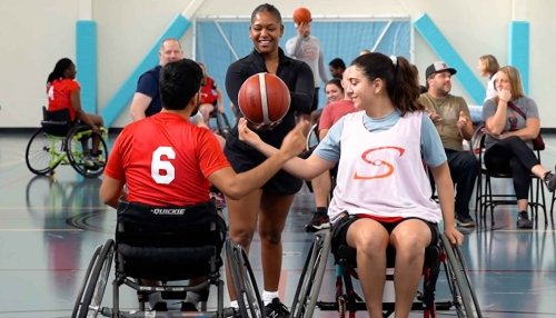 Occupational therapy students play basketball in specialized wheelchairs.